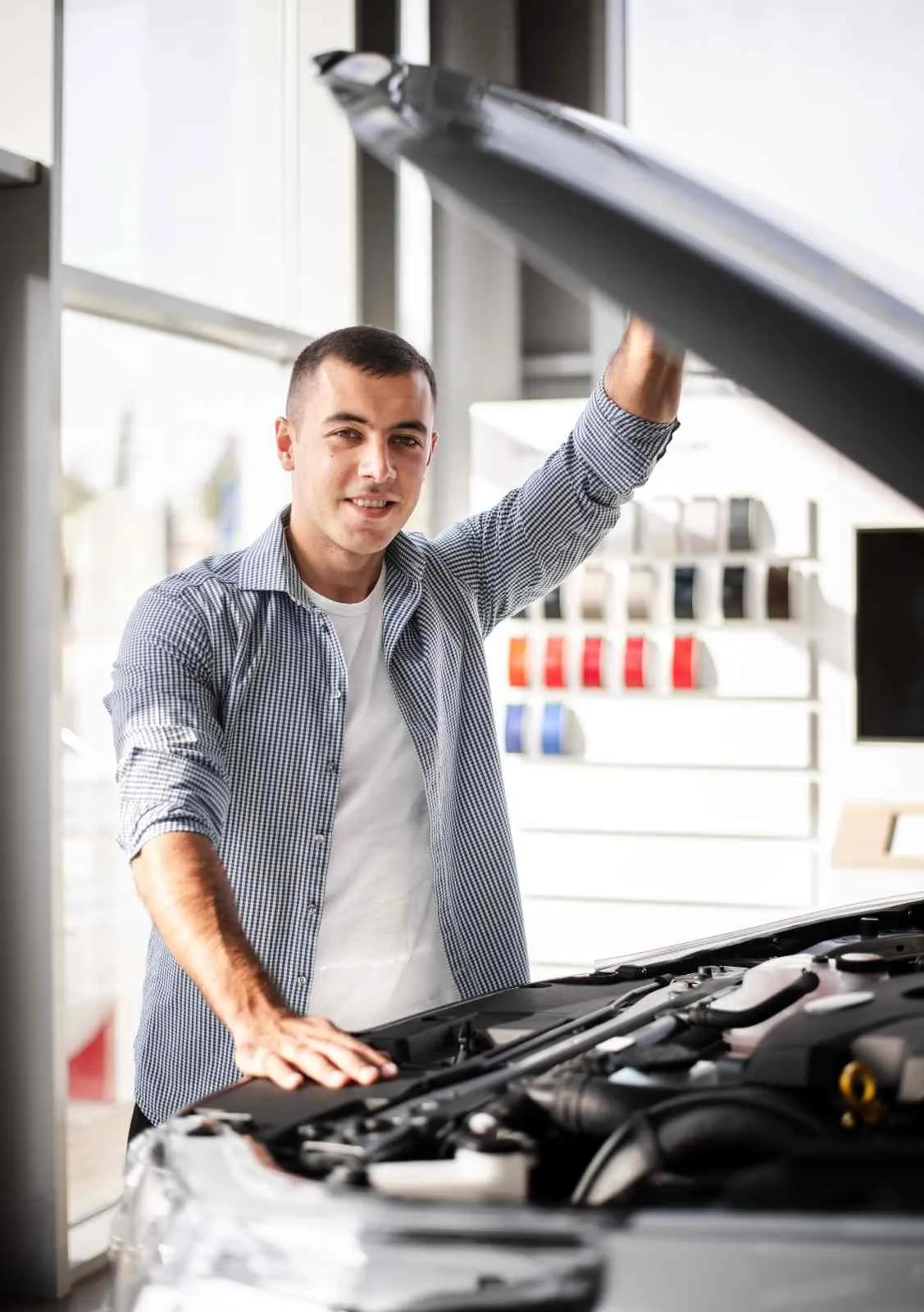 Driver standing at an open car hood looking over the engine